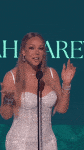a woman in a white dress stands in front of a microphone in front of a sign that says share