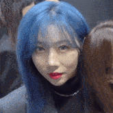 a girl with blue hair and red lips is standing next to another girl .