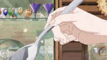 a person is holding a spoon in front of a glass display