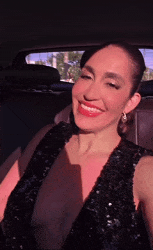 a woman in a black dress is sitting in the back seat of a car