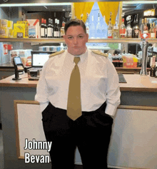 a man in a white shirt and gold tie is standing in front of a bar with the name johnny bevan on the bottom