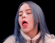a woman with blue hair is making a funny face with her tongue out .
