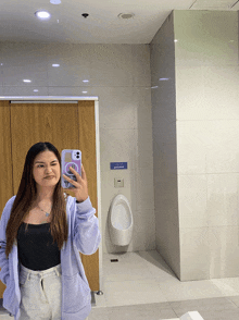 a woman taking a selfie in a public restroom