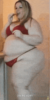 a very fat woman in a red bra and red bikini is eating something .
