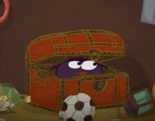 a purple cartoon character is peeking out of a treasure chest next to a soccer ball