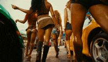 a group of women are walking down a street in shorts and boots