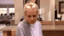 a woman is sitting at a table in a living room with a bun in her hair .