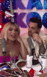 a man and a woman are sitting in front of microphones .