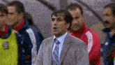 a man in a suit and tie stands in front of a group of men