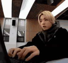 a young man is typing on a laptop in a room .