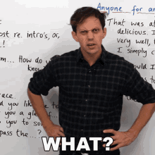 a man in a plaid shirt stands in front of a white board with the word what written on it