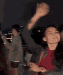 a woman is smiling and waving her hand in the air while standing in a crowd .