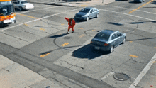 a man in a red suit is crossing a street with a bus in the background