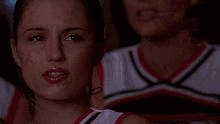 a close up of a woman 's face with a cheerleader behind her