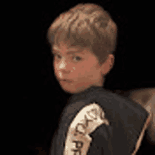 a young boy is wearing a black jacket with a ribbon on the back .