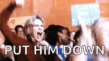 a woman in a crowd screaming with the words put him down