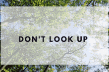 a sign that says ' don 't look up ' on it with trees in the background