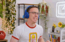 a man wearing headphones and a taco bell shirt is smiling