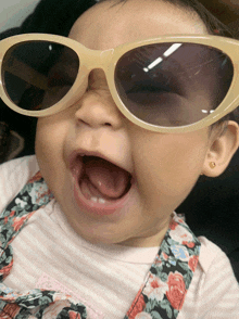 a baby wearing sunglasses and a floral dress