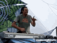 a man is standing in front of a cme keyboard and dancing .
