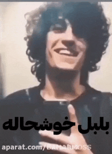 a man with curly hair is smiling while taking a selfie with a cell phone .