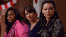 three women are sitting next to each other and one of them is wearing a pink sweatshirt