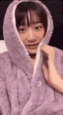 a woman wearing a purple robe with a hood on her head is smiling .