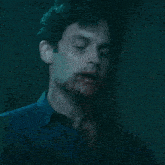 a close up of a man 's face with a blue shirt on