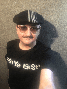 a man wearing a hat and sunglasses is wearing a shirt that says ' ny east '
