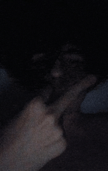 a person 's hand is covering their mouth in the dark