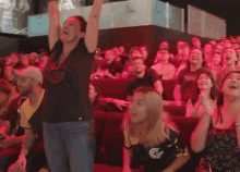 a woman in a black shirt with the letter g on it is cheering in a crowd
