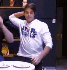 a man wearing a star wars sweatshirt is standing in front of a table .