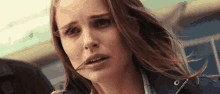 a close up of a woman 's face with hair blowing in the wind