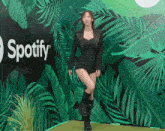 a woman dancing in front of a spotify wall