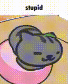 a cartoon cat is laying on top of a pink heart with the word stupid above it .