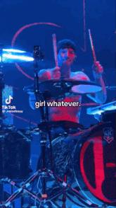 a shirtless man is playing drums on a stage with a caption that says ' girl whatever ' .
