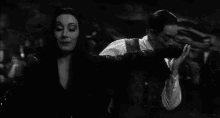 a black and white photo of a man and a woman dancing together .