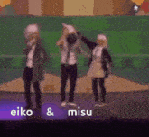 a group of people are standing on a stage with the words eiko & misu written on the bottom