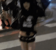 a woman in a black shirt and shorts is standing on a crosswalk .