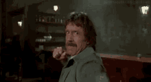 a man with a mustache is making a funny face while throwing a fist in the air .