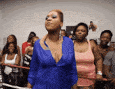 a woman in a blue shirt is standing in a crowd
