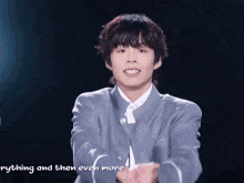 a young man in a gray jacket is smiling with the words " everything and then even more " above him