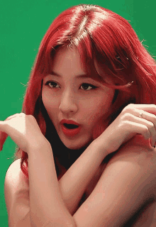 a close up of a woman 's face with red hair on a green background