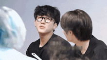 a man wearing glasses looks up at another man