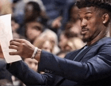 a man in a suit holds a piece of paper in his hand