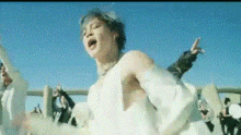 a woman in a white dress is standing in front of a blue sky .