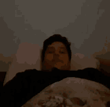 a blurry picture of a person laying in bed with their eyes closed and a pink pillow .