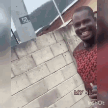 a man is smiling in front of a brick wall with a sign that says 50