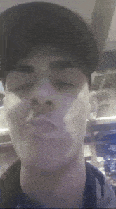 a man wearing a baseball cap is making a funny face with his eyes closed .