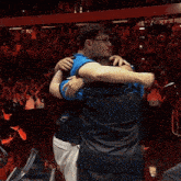 two men hugging with one wearing a sports jersey